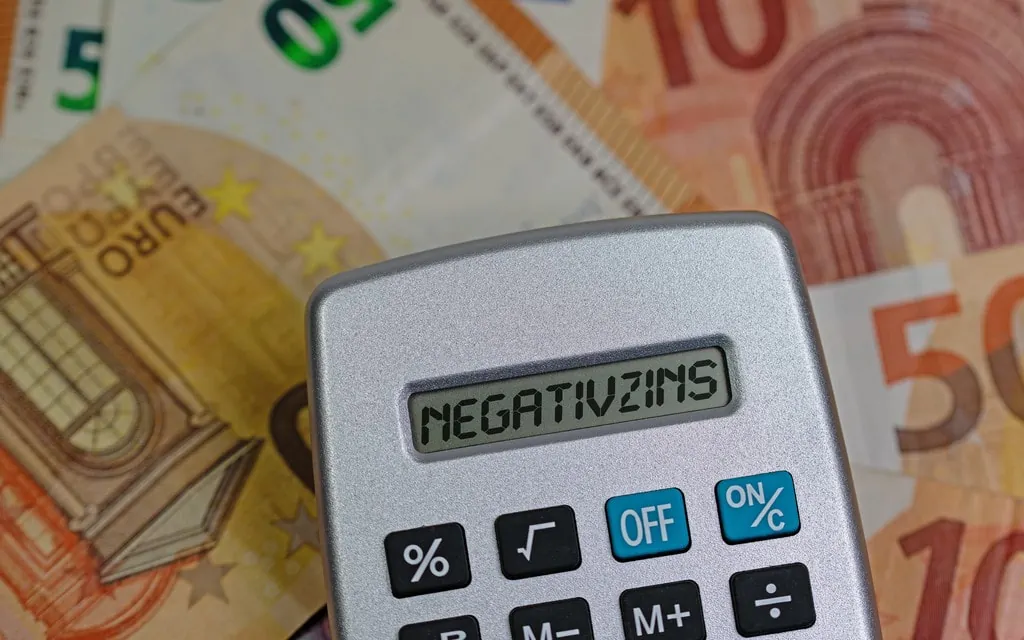 Taschenrechner auf Geldscheinen mit dem Text Negativzins 