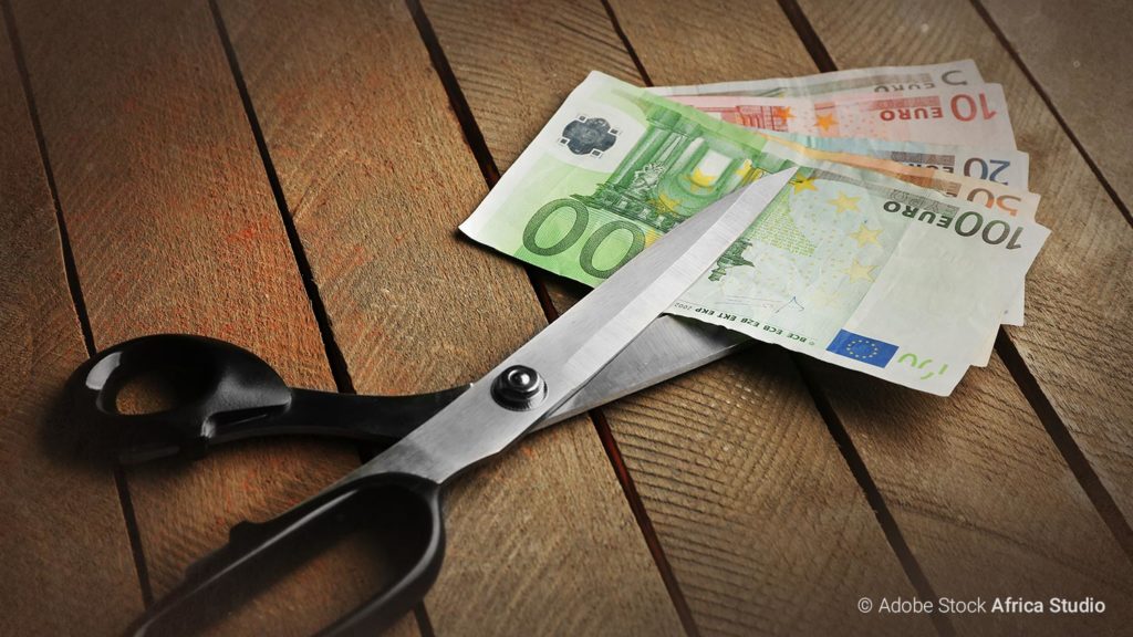 Geldentwertung - viele Euroscheine liegen zwischen den Scherenscheiben einer großen Schere