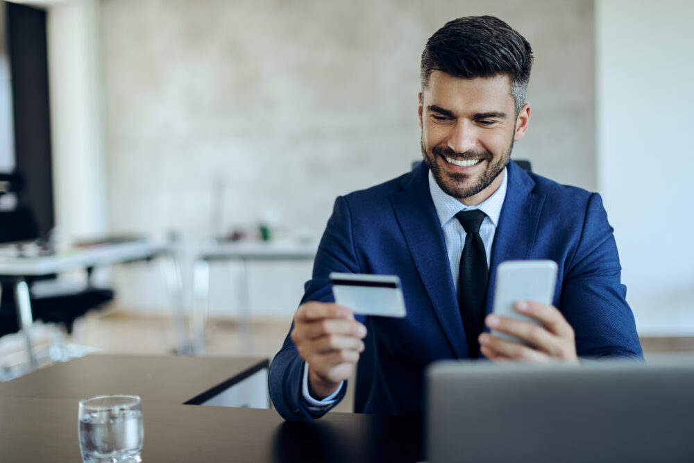 happy entrepreneur online banking with credit card mobile phone office